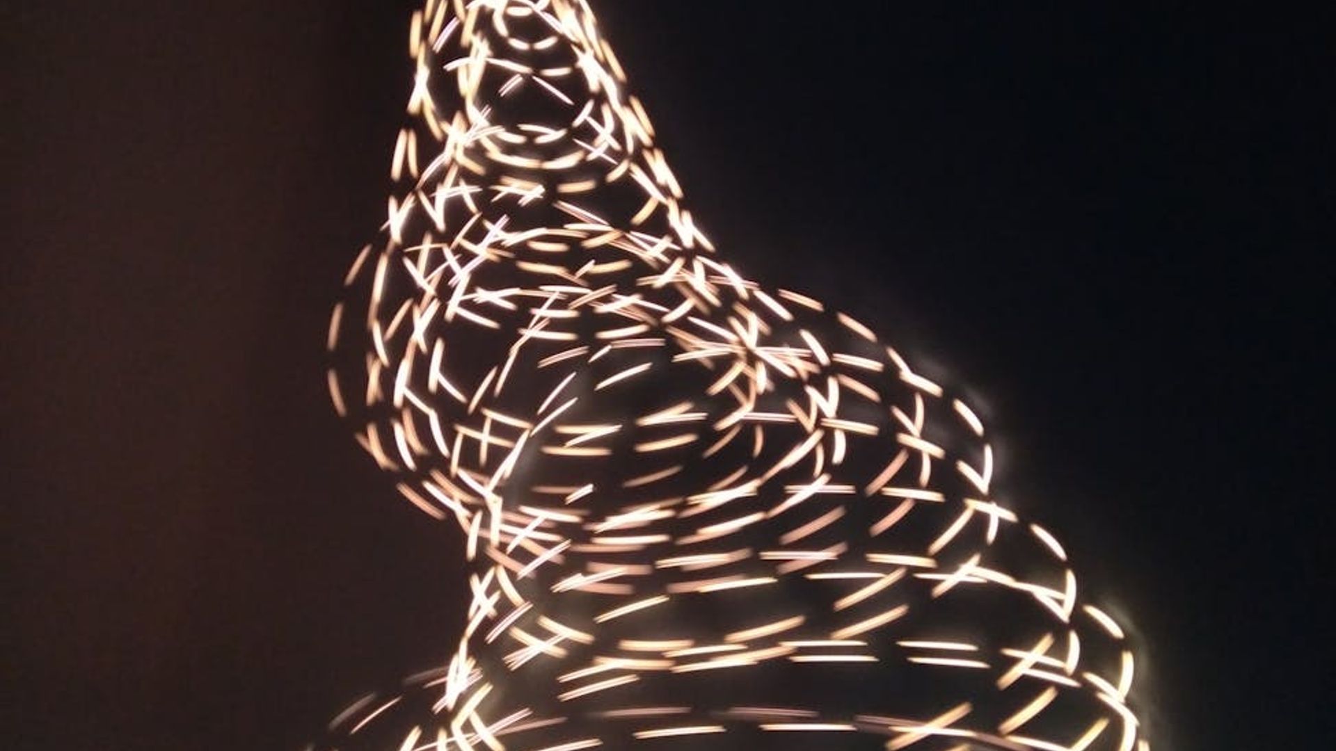 Abstract visualization of rhythmic light trails in a dark space.